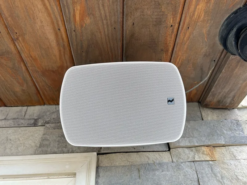 Russound outdoor speaker installed beneath a covered exterior ceiling.