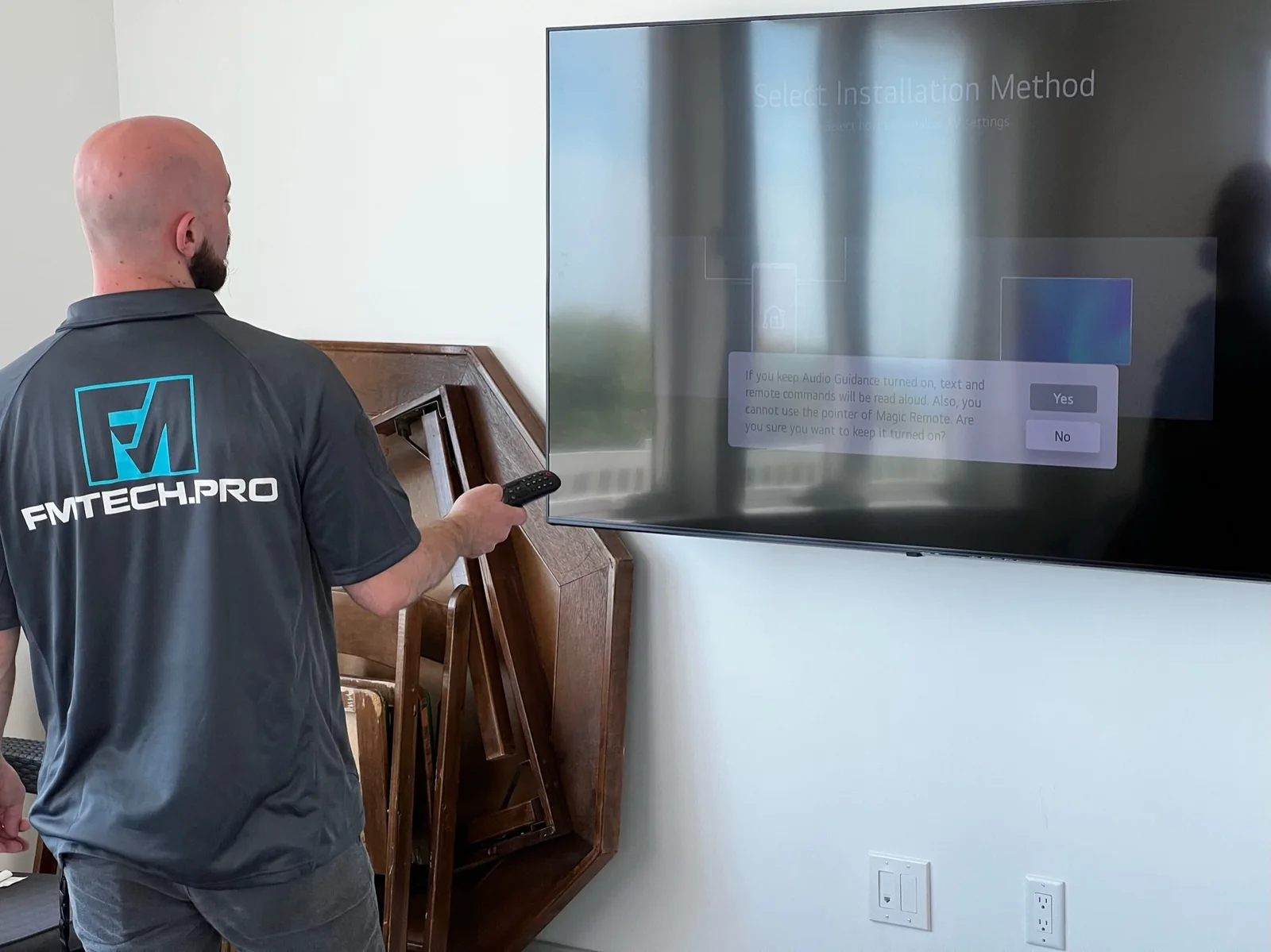 FM Tech technician configuring a wall-mounted television during an installation.